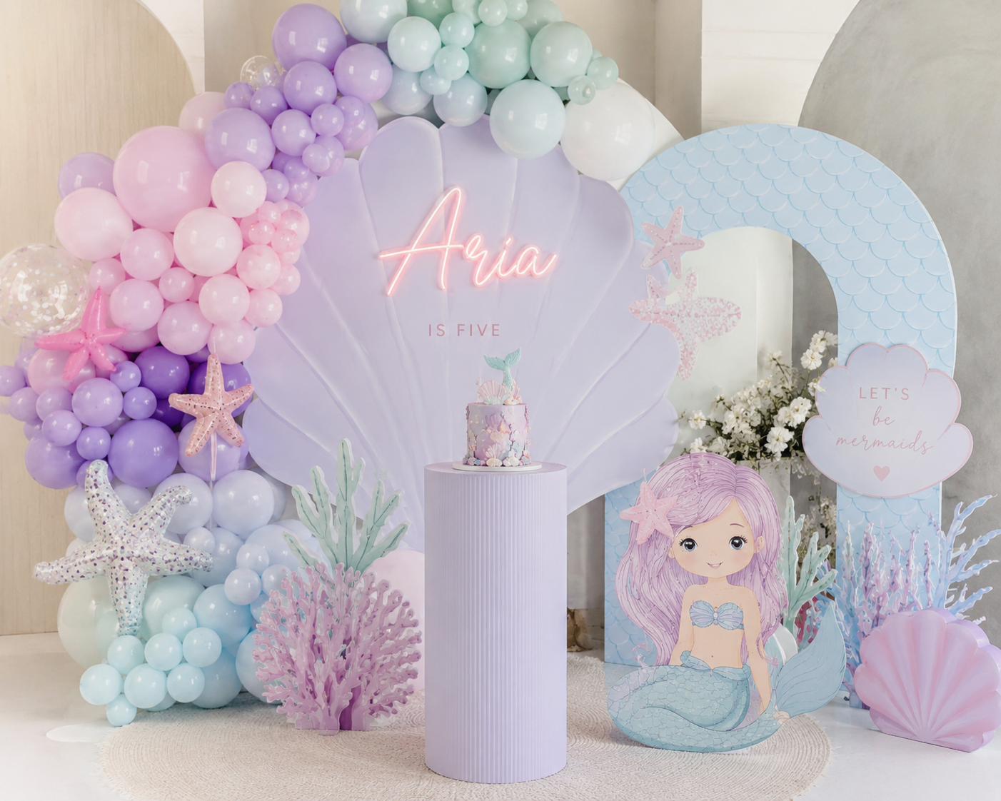 Mermaid themed birthday backdrop with pastel balloons, shell details and a personalised name sign
